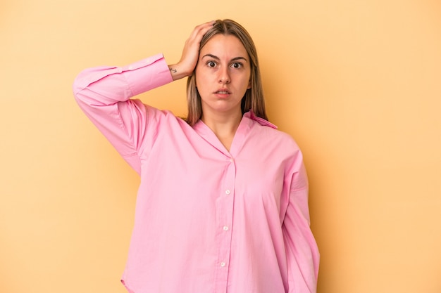 Jonge blanke vrouw geïsoleerd op gele achtergrond geschokt, ze heeft een belangrijke vergadering onthouden.