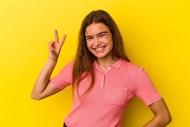 Jonge blanke vrouw geïsoleerd op gele achtergrond met nummer twee met vingers.