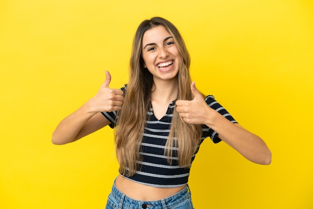 Jonge blanke vrouw geïsoleerd op gele achtergrond met thumbs up gebaar en glimlachen