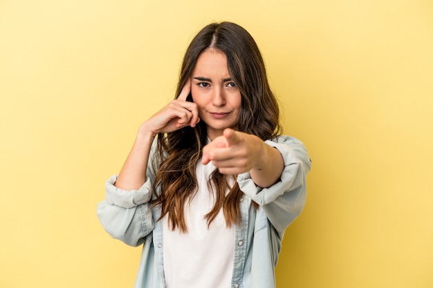 Jonge blanke vrouw geïsoleerd op gele achtergrond wijzende tempel met vinger, denken, gericht op een taak.