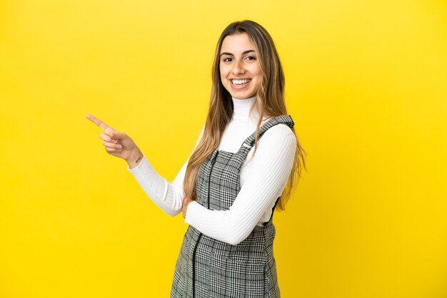 Jonge blanke vrouw geïsoleerd op gele achtergrond wijzende vinger naar de zijkant