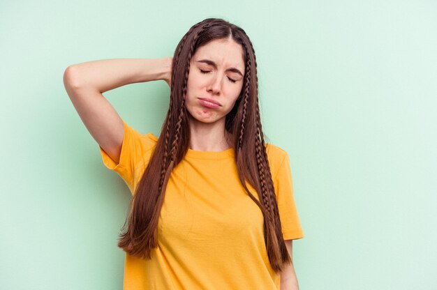 Jonge blanke vrouw geïsoleerd op groene achtergrond moe en erg slaperig hand op het hoofd houden