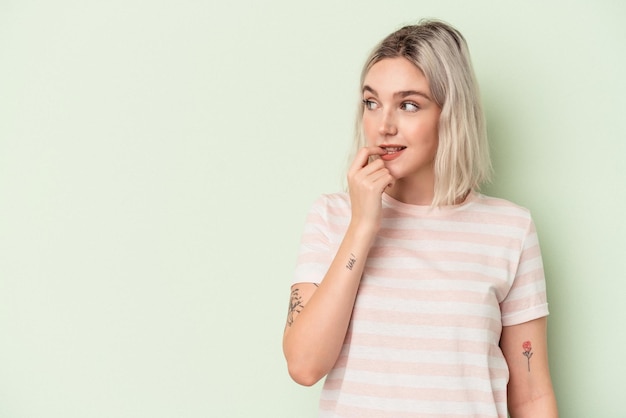 Jonge blanke vrouw geïsoleerd op groene achtergrond ontspannen denken over iets kijken naar een kopie ruimte.