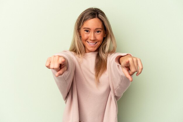 Jonge blanke vrouw geïsoleerd op groene achtergrond vrolijke glimlach wijzend naar voren.