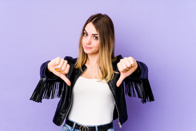 Jonge blanke vrouw geïsoleerd op paars met duim omlaag, teleurstelling concept.