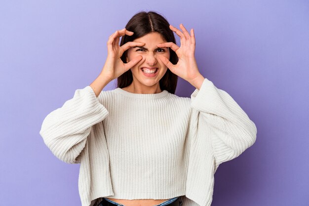 Jonge blanke vrouw geïsoleerd op paarse achtergrond die ogen open houdt om een succeskans te vinden.