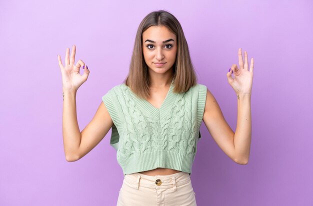 Jonge blanke vrouw geïsoleerd op paarse achtergrond in zen pose