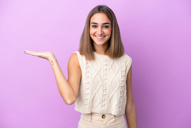 Jonge blanke vrouw geïsoleerd op paarse achtergrond met copyspace denkbeeldig op de palm om een advertentie in te voegen