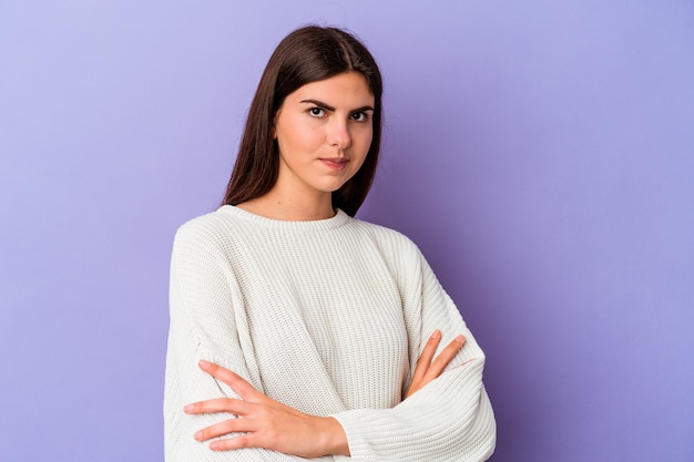 Jonge blanke vrouw geïsoleerd op paarse muur ongelukkig met sarcastische uitdrukking.