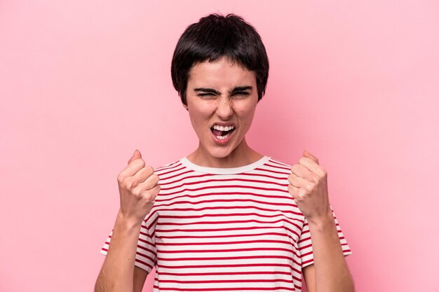 Jonge blanke vrouw geïsoleerd op roze achtergrond boos schreeuwen met gespannen handen.