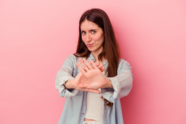 Jonge blanke vrouw geïsoleerd op roze achtergrond die een ontkenningsgebaar doet