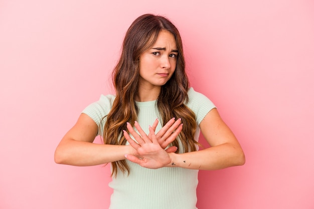 Jonge blanke vrouw geïsoleerd op roze achtergrond die een ontkenningsgebaar doet