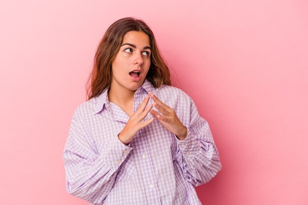 Jonge blanke vrouw geïsoleerd op roze achtergrond die een plan in gedachten maakt, een idee opzet.