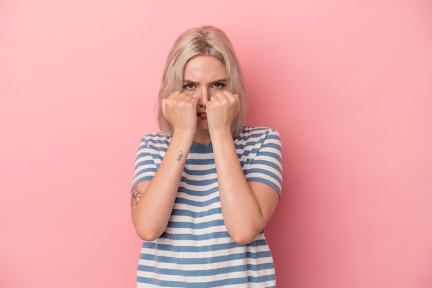 Jonge blanke vrouw geïsoleerd op roze achtergrond die een vuistslag gooit, woede, vecht vanwege een ruzie, boksen.
