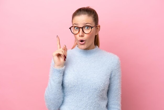 Jonge blanke vrouw geïsoleerd op roze achtergrond die van plan is de oplossing te realiseren terwijl ze een vinger opheft