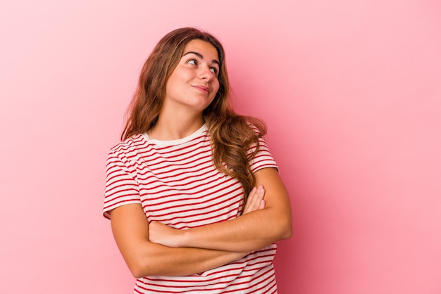 Jonge blanke vrouw geïsoleerd op roze achtergrond dromen van het bereiken van doelen en doeleinden