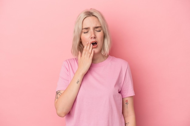 Jonge blanke vrouw geïsoleerd op roze achtergrond geeuwen met een vermoeid gebaar dat de mond bedekt met de hand