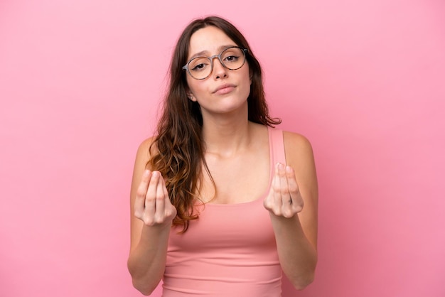 Jonge blanke vrouw geïsoleerd op roze achtergrond geld verdienen gebaar maar is geruïneerd