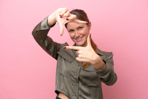 Jonge blanke vrouw geïsoleerd op roze achtergrond gericht gezicht Framing symbol