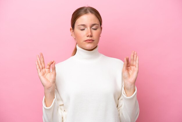 Jonge blanke vrouw geïsoleerd op roze achtergrond in zen pose