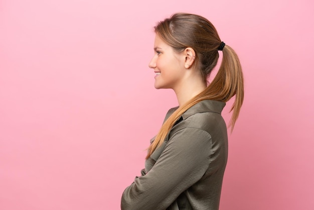 Jonge blanke vrouw geïsoleerd op roze achtergrond in zijpositie