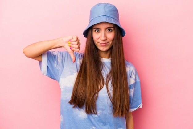 Jonge blanke vrouw geïsoleerd op roze achtergrond met een afkeer gebaar, duim omlaag. Onenigheid begrip.