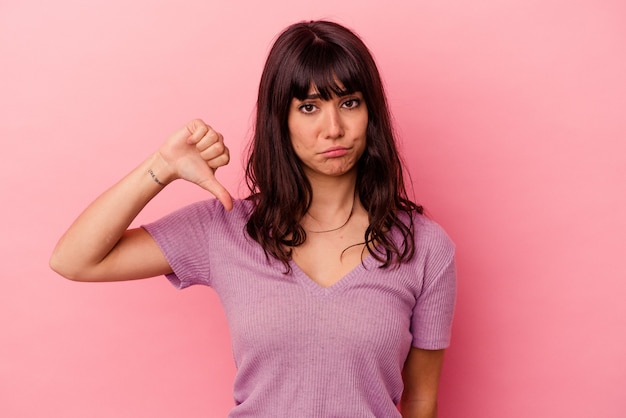 Jonge blanke vrouw geïsoleerd op roze achtergrond met een afkeer gebaar, duimen naar beneden. Meningsverschil concept.