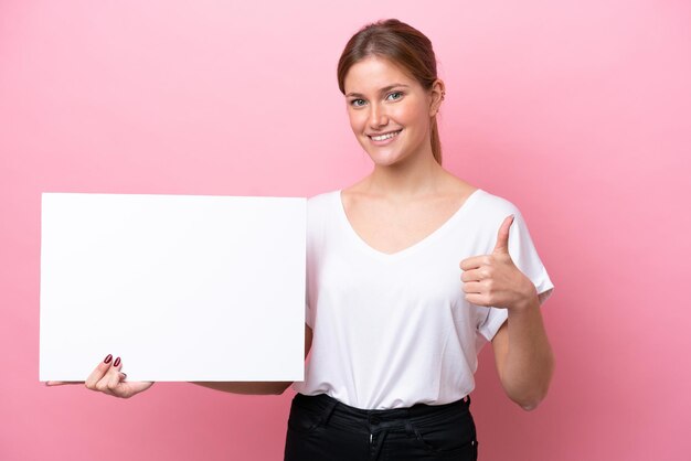 Jonge blanke vrouw geïsoleerd op roze achtergrond met een leeg bordje met duim omhoog