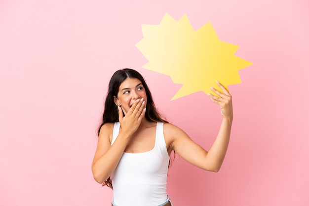 Jonge blanke vrouw geïsoleerd op roze achtergrond met een lege tekstballon met verbaasde uitdrukking