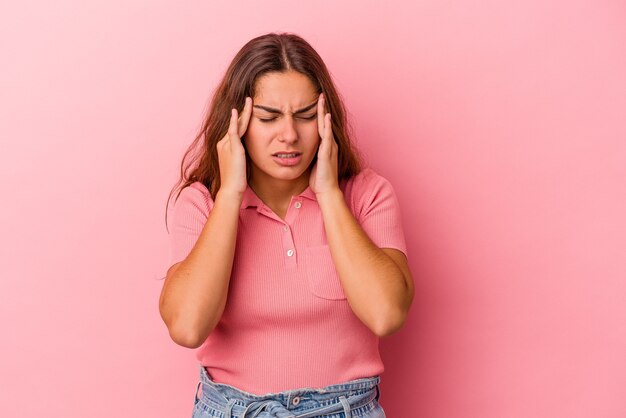 Jonge blanke vrouw geïsoleerd op roze achtergrond met hoofdpijn, aanraken van de voorkant van het gezicht.