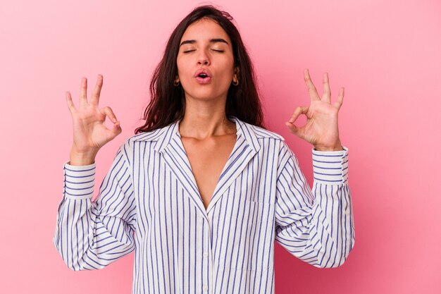 Jonge blanke vrouw geïsoleerd op roze achtergrond ontspant na een zware werkdag, ze voert yoga uit.