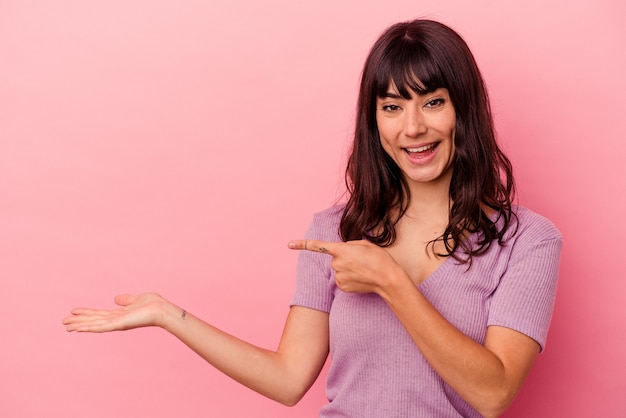 Jonge blanke vrouw geïsoleerd op roze achtergrond opgewonden houden a op palm.