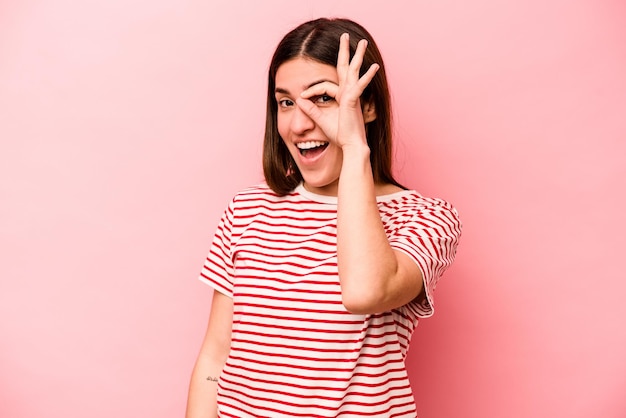 Jonge blanke vrouw geïsoleerd op roze achtergrond opgewonden houden ok gebaar in de gaten