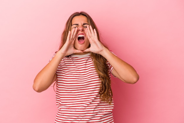 Jonge blanke vrouw geïsoleerd op roze achtergrond opgewonden schreeuwen naar voren.