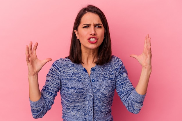 Jonge blanke vrouw geïsoleerd op roze achtergrond schreeuwen van woede.