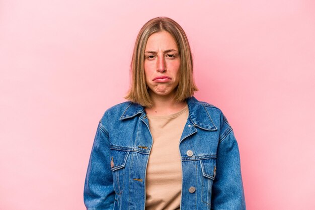 Jonge blanke vrouw geïsoleerd op roze achtergrond verdrietig serieus gezicht voelt zich ellendig en ontevreden