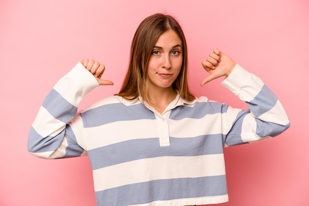 Jonge blanke vrouw geïsoleerd op roze achtergrond voelt zich trots en zelfverzekerd voorbeeld om te volgen