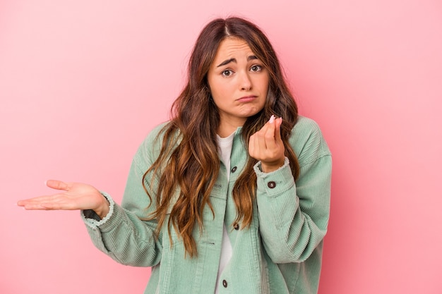 Jonge blanke vrouw geïsoleerd op roze achtergrond waaruit blijkt dat ze geen geld heeft.