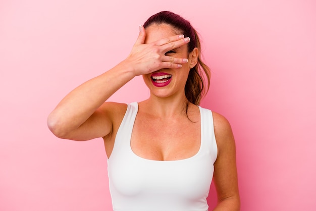 Jonge blanke vrouw geïsoleerd op roze lacht hardop terwijl ze de hand op de borst houdt.