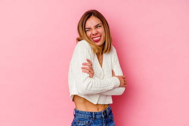 Jonge blanke vrouw geïsoleerd op roze muur grappige en vriendelijke tong uitsteekt.