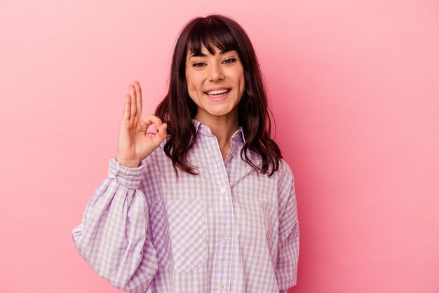 Jonge blanke vrouw geïsoleerd op roze muur vrolijk en zelfverzekerd tonend ok gebaar.