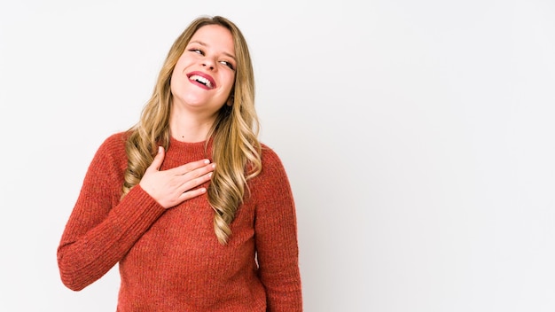 Jonge blanke vrouw geïsoleerd op wit lacht hardop hand op de borst te houden.