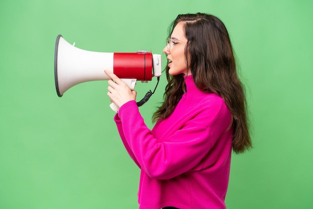 Jonge blanke vrouw geïsoleerd over een geïsoleerde achtergrond schreeuwend door een megafoon