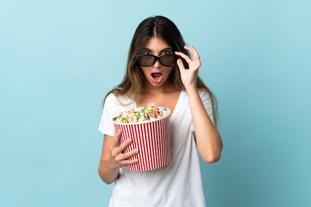 Jonge blanke vrouw geïsoleerd verrast met 3D-bril en popcorn houden