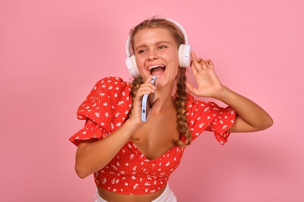 Jonge blanke vrouw in koptelefoon zingt met telefoon in plaats van microfoon