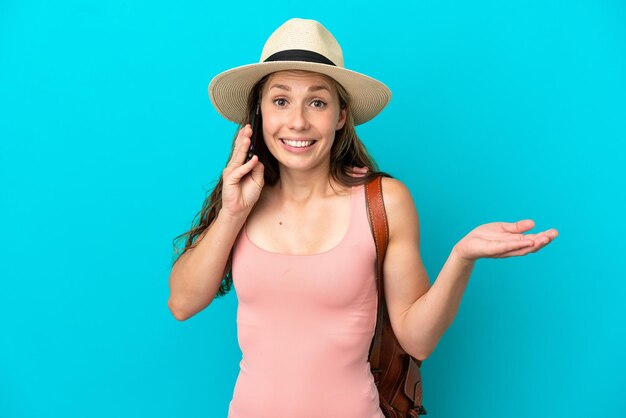 Jonge blanke vrouw in zomervakantie geïsoleerd op blauwe achtergrond die een gesprek voert met de mobiele telefoon met iemand