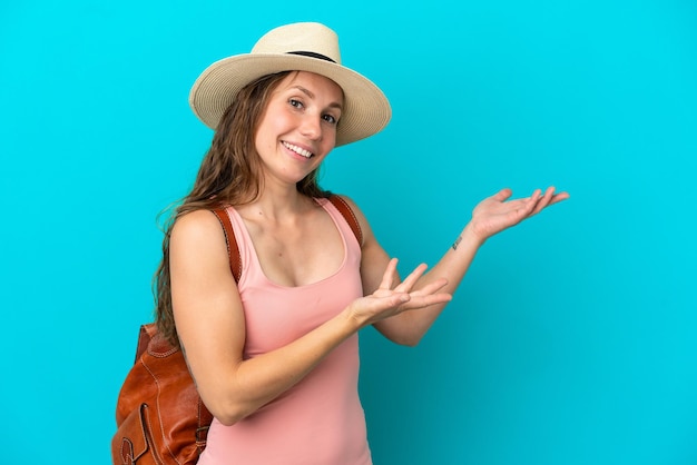Jonge blanke vrouw in zomervakantie geïsoleerd op een blauwe achtergrond die de handen naar de zijkant uitstrekt om uit te nodigen om te komen