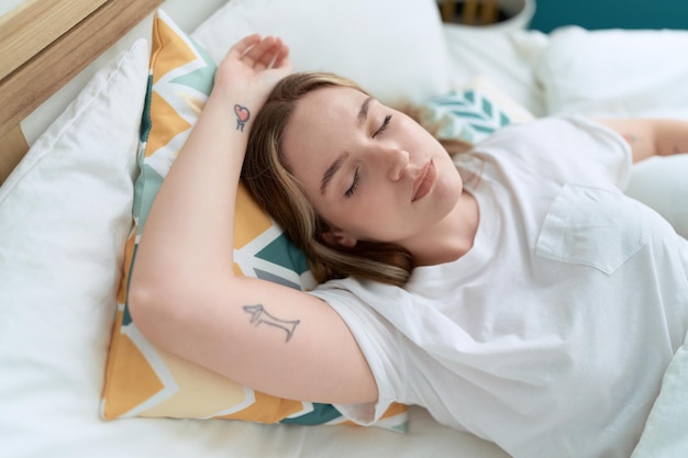 Jonge blanke vrouw liggend op bed slapen in de slaapkamer