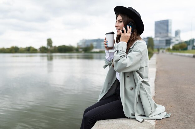 Jonge blanke vrouw manager freelancer rustend in de buurt van de oever van de rivier met een kopje