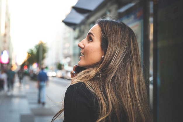 Jonge blanke vrouw met behulp van een smartphone op de Gran Via Avenue in Madrid, Spanje.